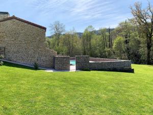 a stone wall in a yard with a grass field at 2 Apartamentos en villa con piscina privada en Asturias El Marquesau in Noriega
