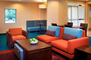una sala de espera con sillas naranjas y azules y una mesa en Sonesta ES Suites Detroit Warren, en Warren