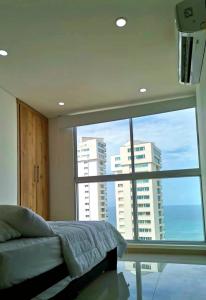 a bedroom with a bed and a large window at Apartamento frente al mar Rodadero Santa Marta in Santa Marta