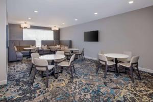 a dining room with tables and chairs and a tv at Sonesta ES Suites Atlanta Kennesaw Town Center in Kennesaw