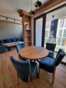 una sala da pranzo con tavolo in legno e sedie blu di Apartman Milovanović a Divčibare Altre 10 foto