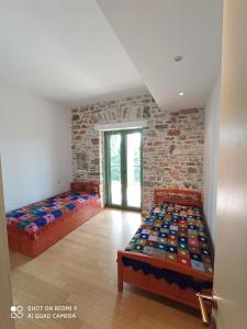 1 dormitorio con 2 camas y pared de ladrillo en Villa Sklithro in the heart of the forest with magnificent view of the sea just 10 minutes from it, en AgiaKampos