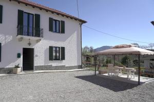 a building with an umbrella and a table and chairs at Cascina Riva in Leggiuno