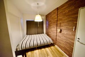 um pequeno quarto com uma cama no canto em Guest House Re-worth Yabacho1 402 em Nagoia