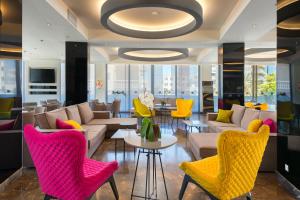 a lobby with yellow and pink chairs and tables at Semiramis City Hotel in Rhodes Town