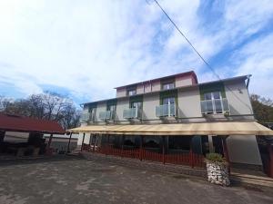 a white building with a red fence in front of it at Motel Šofér in Volkovce