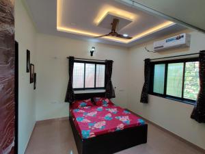 a bedroom with a bed in a room with windows at Rama Niwas Beach Home Stay in Pawas