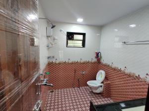 a bathroom with a toilet and a red tile floor at Rama Niwas Beach Home Stay in Pawas