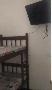 uma televisão de ecrã plano pendurada numa parede ao lado de uma cama em Augusta Jardins Home em São Paulo