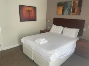 una camera da letto con un grande letto con lenzuola bianche di The Moorings Hotel a Edmondsley