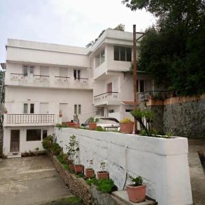 Kumaragiri Cottages Kodaikanal في كوديكانال: مبنى أبيض أمامه نباتات خزف
