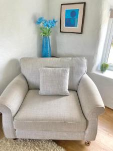 un divano in soggiorno con un vaso blu di Idyllic Cornish Cottage, Superking bed, private garden dogs welcome a Truro