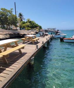 uma doca com mesas de piquenique e barcos na água em Mo Place em Paradera