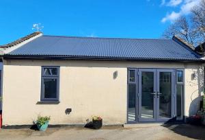 a white house with a large glass door at Sycamore Lodge Kent With EV Zappi type 2, swimming pool for a fee in Sellindge