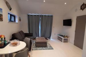 a living room with a couch and a table at Sycamore Lodge Kent With EV Zappi type 2, swimming pool for a fee in Sellindge
