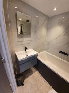a white bathroom with a sink and a bath tub at Sycamore Lodge Kent With EV Zappi type 2 in Sellindge