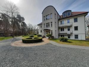 een groot wit huis met een ronde oprit bij Haus am Kölpinsee FW Seejuwel Objekt ID 13833-4 in Kölpinsee