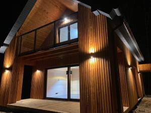 una casa de madera con una escalera por la noche en Mazurskie Klimaty - dom z widokiem na jezioro en Tomaszkowo