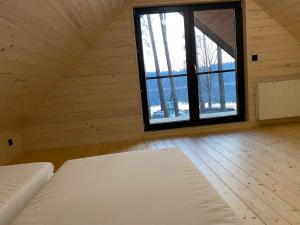um quarto com uma cama e uma grande janela em Mazurskie Klimaty - dom z widokiem na jezioro em Tomaszkowo