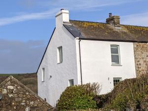 a white house with a chimney on top of it at Millmoor Cottage - Broad Haven in Broad Haven