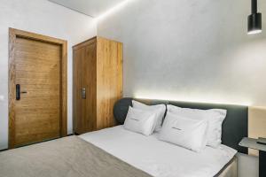 1 dormitorio con cama con almohadas blancas y puerta de madera en Ribas Rooms Lutsk, en Lutsk
