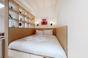um pequeno quarto com uma cama com lençóis brancos em Spacious studio flat in Forest Gate em Londres