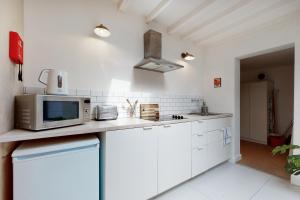 een keuken met witte kasten en een magnetron bij Spacious studio flat in Forest Gate in Londen