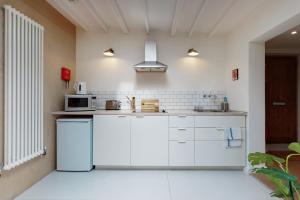 a white kitchen with a refrigerator and a microwave at Spacious studio flat in Forest Gate in London