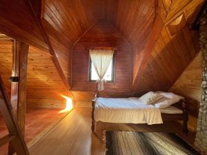 Bett in einem Holzzimmer mit Fenster in der Unterkunft Korbielówka in Korbielów