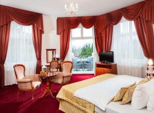 a bedroom with a bed and a table and chairs at Imperial Spa & Kurhotel in Františkovy Lázně