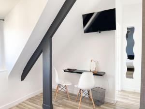 a room with a desk and two chairs and a tv at La Marine in Carnac