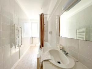 a white bathroom with a sink and a mirror at La Marine in Carnac