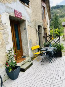 een patio met een tafel en stoelen voor een gebouw bij Le gîte de la vallée du Douctouyre in Dun