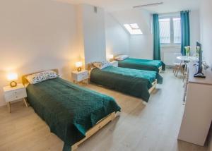 1 dormitorio con 2 camas con edredones verdes y mesa en Centrum Edukacji Ekologiczno-Turystycznej en Myczków