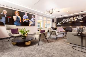 a living room with chairs and tables and a painting at maakt Hotel in Stralsund