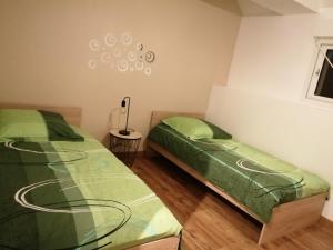 2 camas en una habitación con sábanas verdes en Le Tiluce, en Aunay-sur-Odon