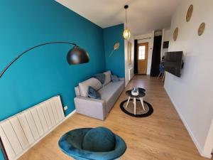 sala de estar con sofá y pared azul en L'Azimut de Châtel-Guyon, en Châtel-Guyon