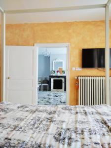 1 dormitorio con 1 cama y TV en la pared en Maison de village - Suite Baroque cosy et élégante à 1 h de Paris proche Fontainebleau, 