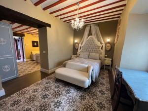 a bedroom with a bed and a chair and a chandelier at RETIRO DEL TEATRO Hotel Boutique y Apartamentos en Almagro in Almagro
