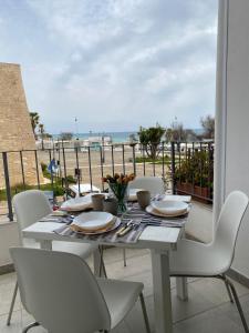 una mesa con sillas blancas y vistas al océano en A 100metri dal mare difronte alla torre saracena. en Campomarino