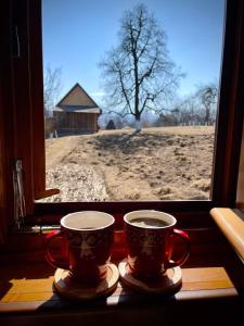dos tazas de café sentadas en el alféizar de la ventana en Pensiunea Agroturistica Casa Pribegilor en Breb