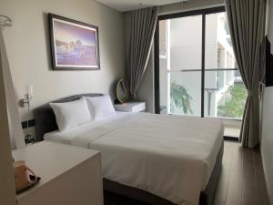 a bedroom with a white bed and a large window at Win Condotel Apec Phú Yên in Tuy Hoa +123 photos