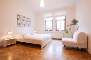a white bedroom with a bed and a chair at Wellness Penzion U Muzea in Liberec