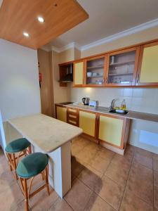 a kitchen with a counter and a table and chairs at Apartamentos Turisticos Alagoa Praia in Altura