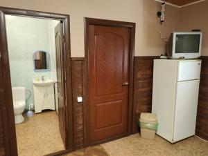La salle de bains est pourvue d'une porte, d'une télévision et d'un réfrigérateur. dans l'établissement Barbecue House, à Vinnytsia