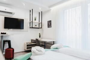 a white room with a bed and a desk and a tv at RIVA Szeged in Szeged