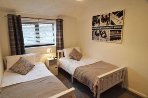 a bedroom with two beds and a window at Mikes at Menai - Stylish & Spacious 3 bed house in Menai Bridge. in Menai Bridge