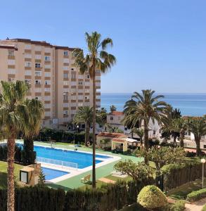uitzicht op een zwembad met palmbomen en de oceaan bij Casa Amaya in Torrox Costa