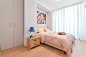 a bedroom with a bed and a table with a lamp at Beautiful new apartment 5 min from Piraeus Port (A2) in Piraeus