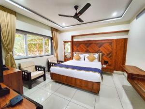 Schlafzimmer mit einem Bett, einem Schreibtisch und einem TV in der Unterkunft Hotel Udupi Inn, Udupi in Udupi